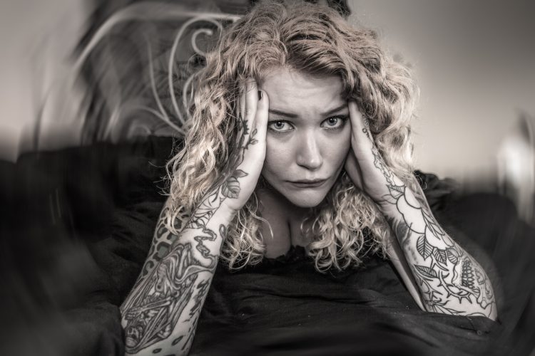 woman with tattoos doing photo shoot to demonstrate how fatigue feels with arthritis