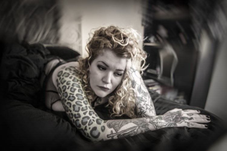 woman with tattoos doing photo shoot to demonstrate how fatigue feels with arthritis