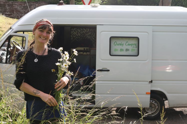 woman picking wildflowers on the side of the road next to the van