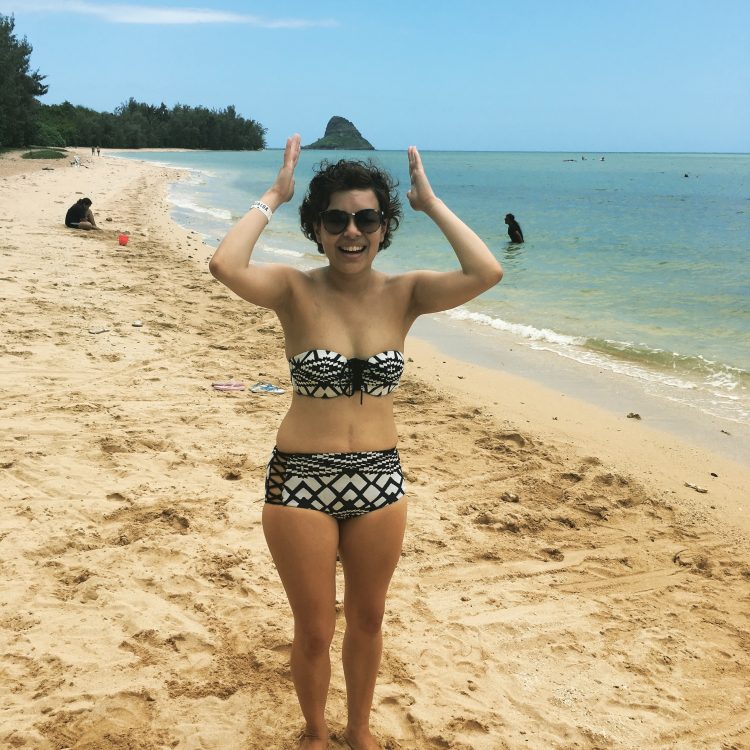 woman in a bikini standing on the beach and laughing