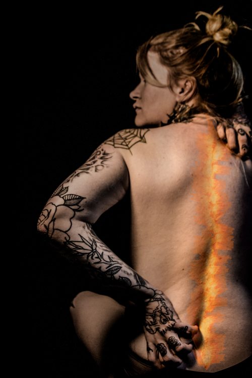woman with tattoos doing a photo shoot to represent her pain from arthritis