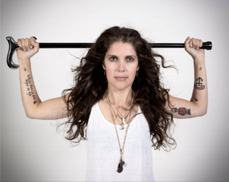 woman in white tank top holding a cane behind her head