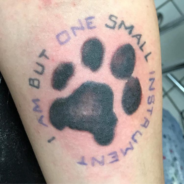dog paw print with writing tattoo on arm