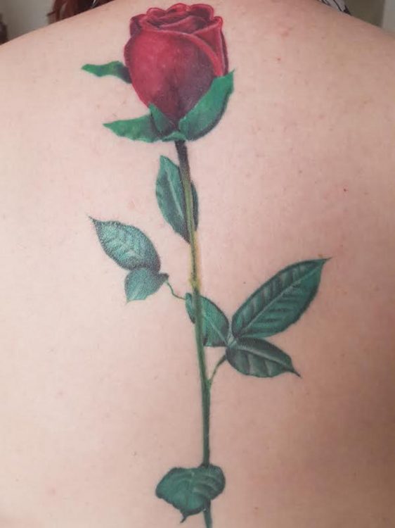 tattoo of a rose on a woman's spine