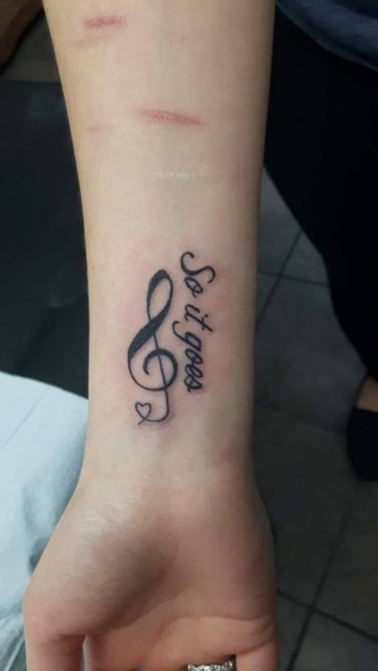 treble clef and words tattooed on wrist