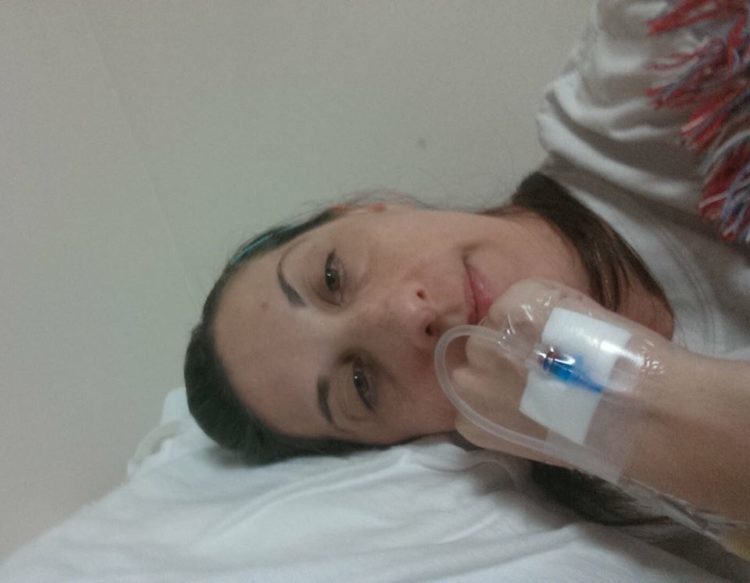 woman lying down with an IV in her hand