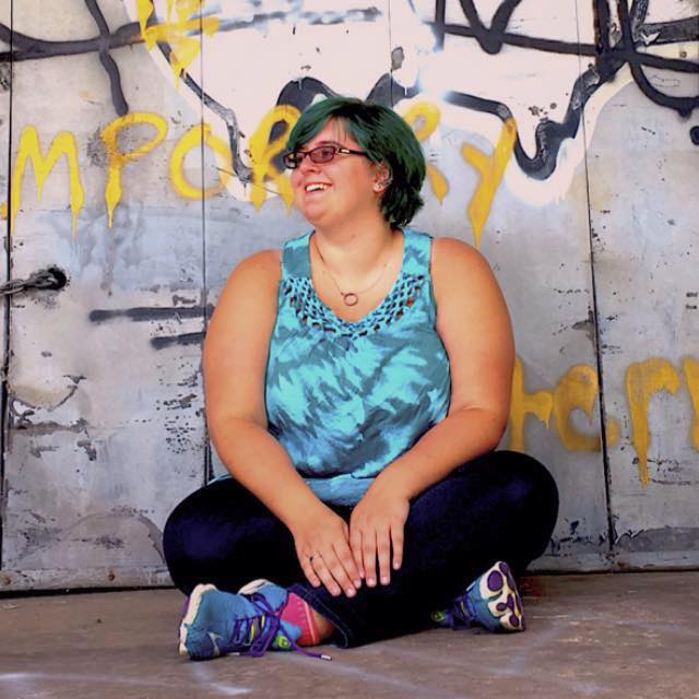 woman sitting outside in workout gear in front of a concrete wall