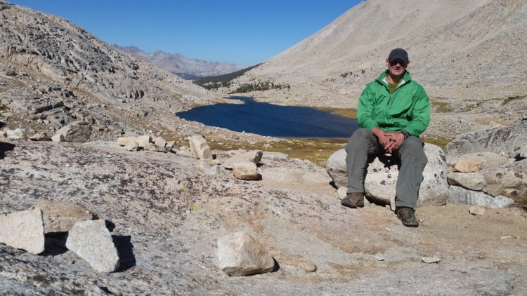 man sitting outside by a lake