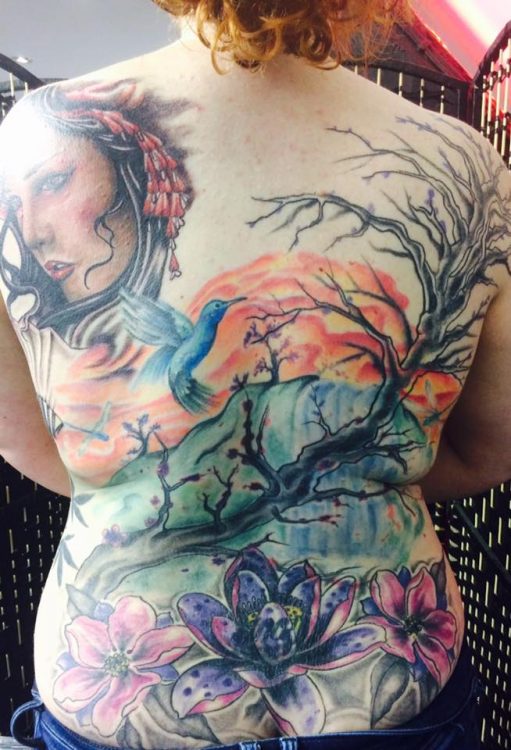 tattoo of landscape with trees and sunset on a woman's back