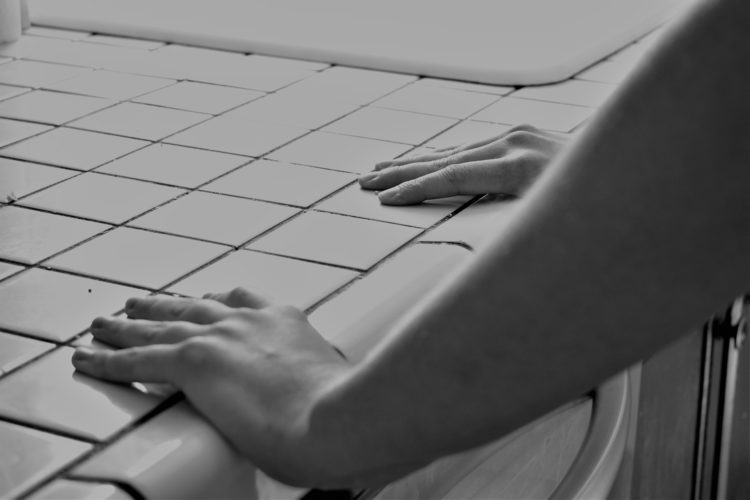 black and white photo of woman's hands gripping tiled counter