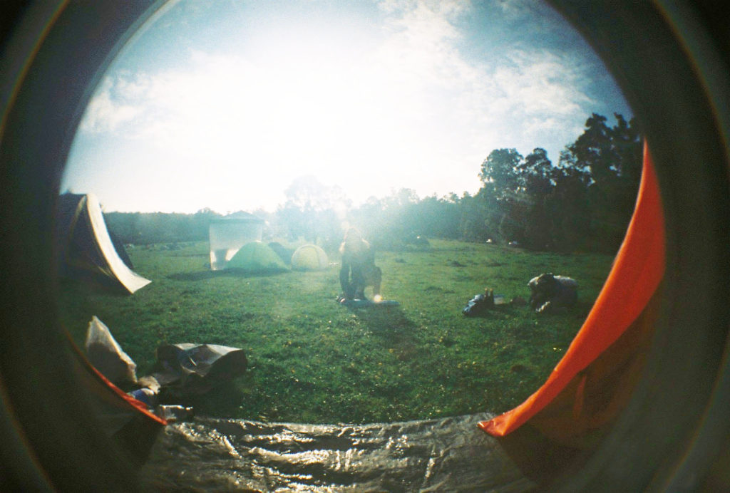 fisheye lens photo of woman packing up tent in sunshine