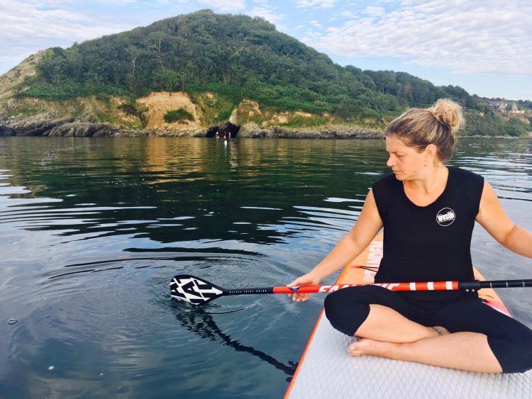 woman sitting on paddleboard on lake