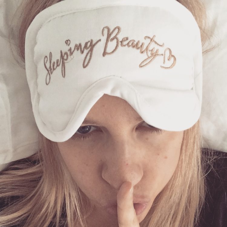 The writer with her sleeping mask resting above her eyes, making the "Shhh" symbol with her finger on her lips.