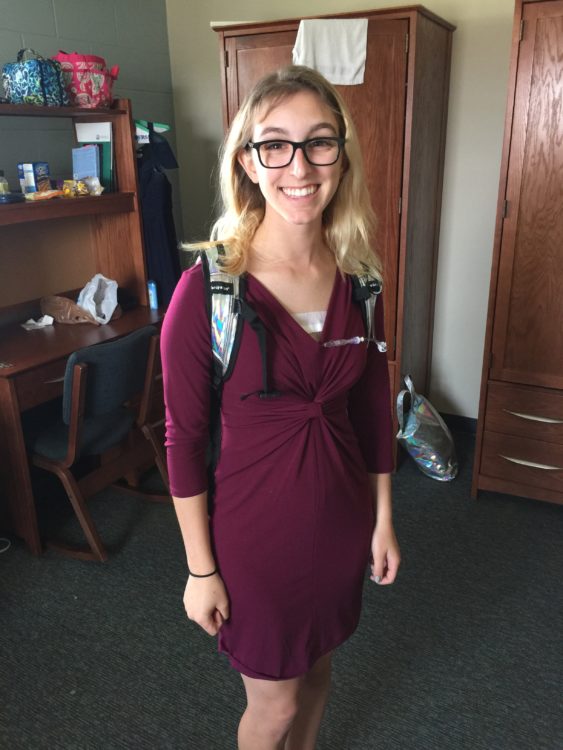 The writer standing with a backpack on, wearing a port.