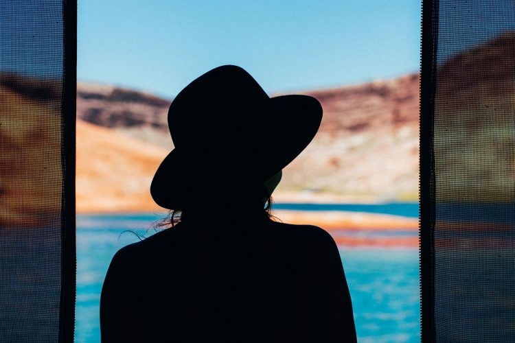 silhouette of a woman against a lake and red hills