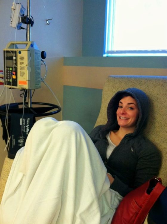 Woman sitting in a medical chair, with a blanket around her.