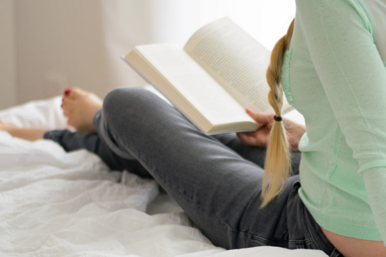 girl sitting in bed reading
