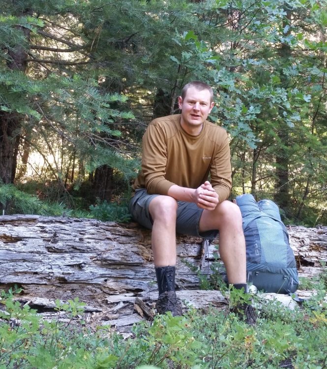man sitting on a log during a backpacking trip