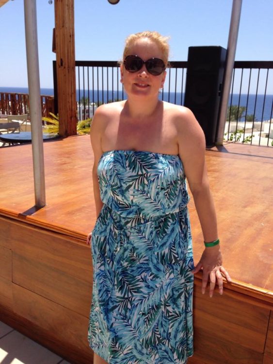 woman in a sun dress and sunglasses on vacation at the beach