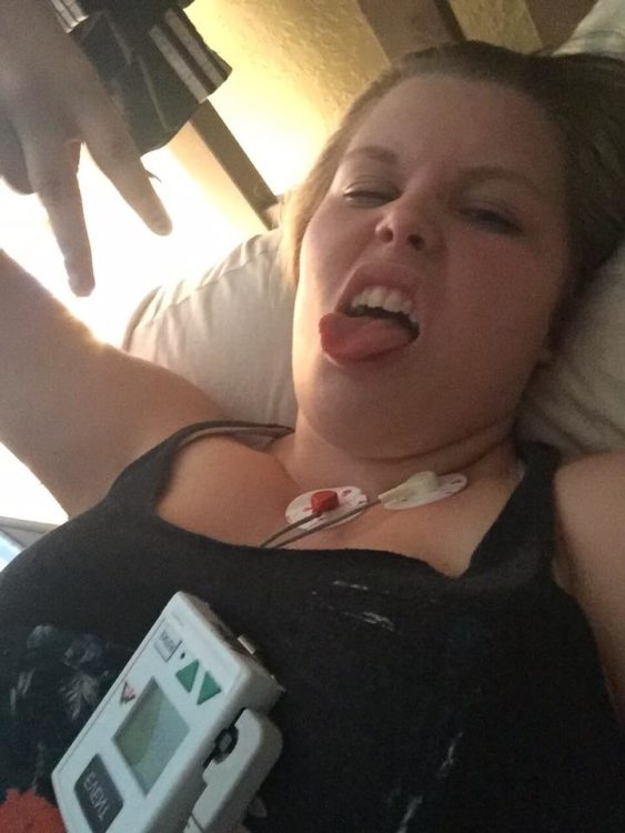 woman lying in bed with monitors on her chest and sticking her tongue out