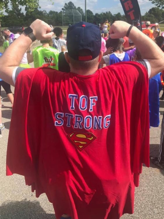 The back of the writer, picturing him with a cape that reads, "TOF strong."