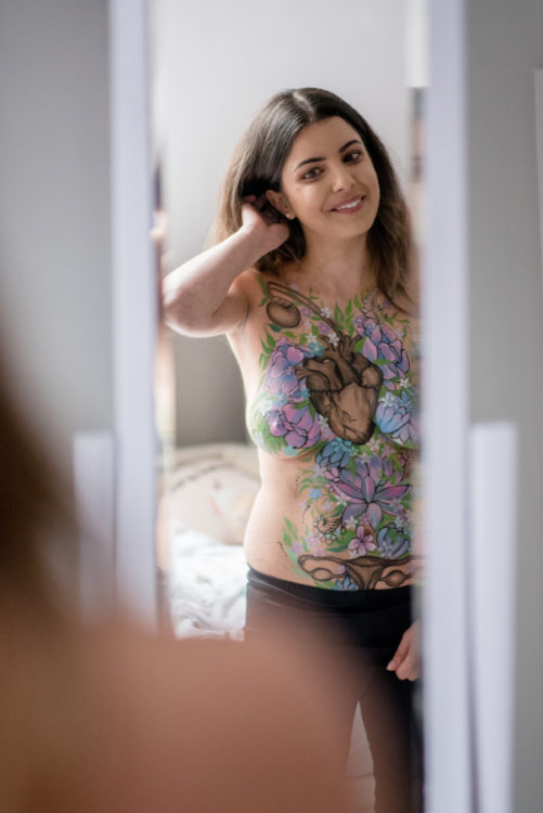 woman standing in front of a mirror with her body painted