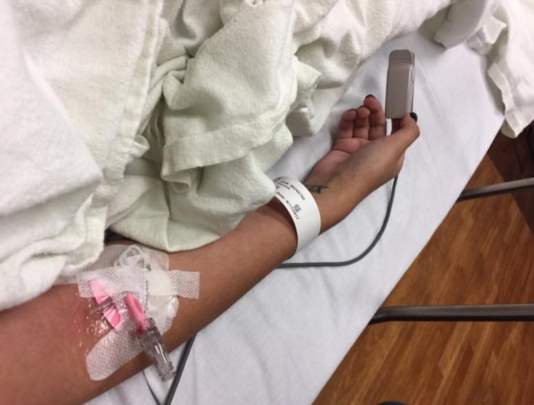 The writer's arm on a hospital bed, with an IV.