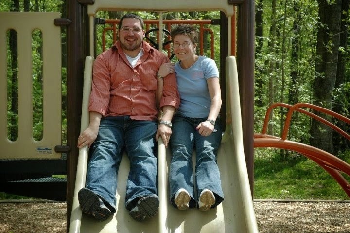 man and woman sitting on a slide at a playground
