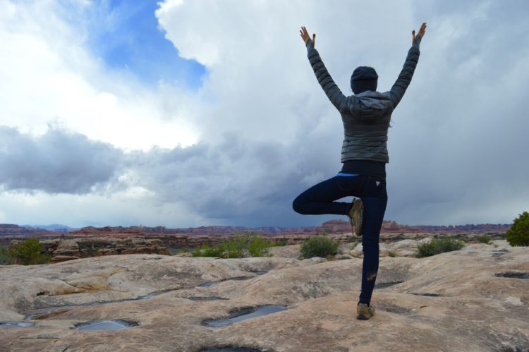 woman standing on mountain with arms up