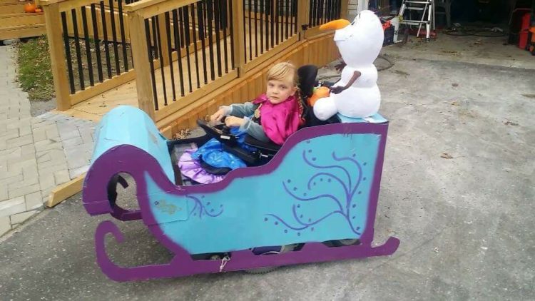 little girl dressed up as Anna from frozen and riding in a sled built around her wheelchair