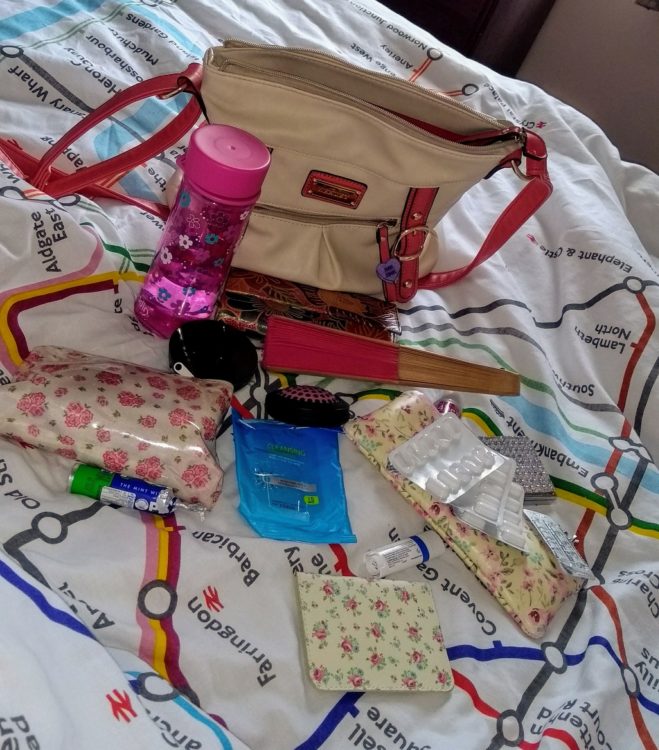 tan purse sitting on bed with medications and small pouches