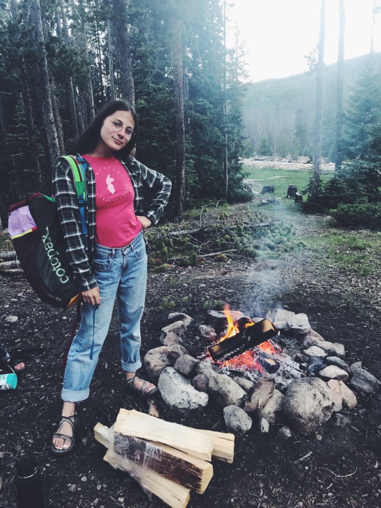 woman posing beside fresh campfire