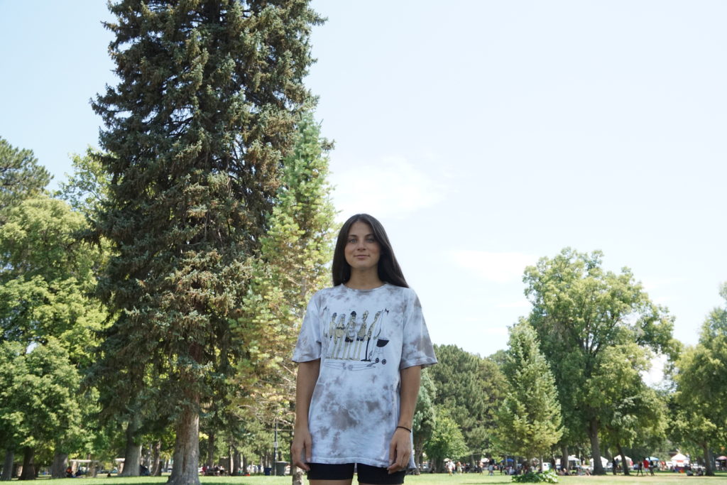 young woman standing in front of trees