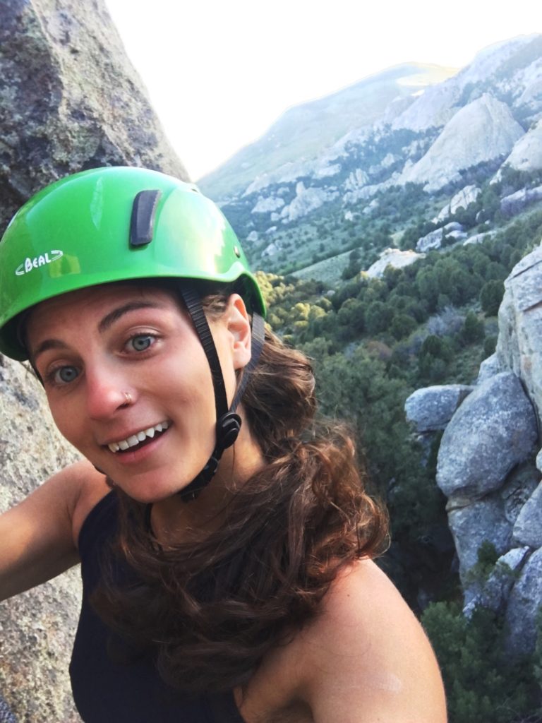 woman climbing side of mountain smiling