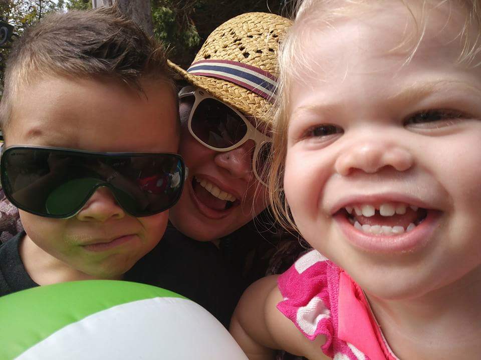 mother smiling with two children wearing sunglasses