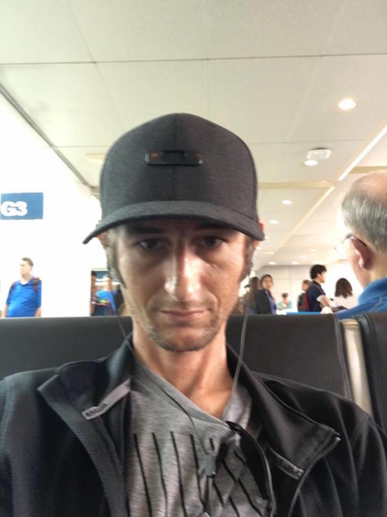 man sitting in an airport wearing a hat