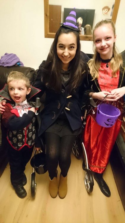 woman sitting on her rollator walker with her two younger siblings before going out trick or treating