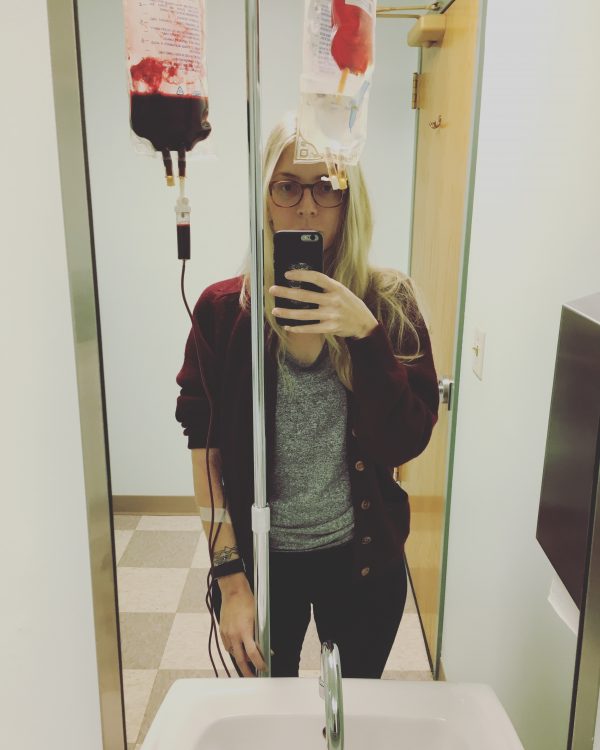 woman taking a selfie while receiving a blood transfusion