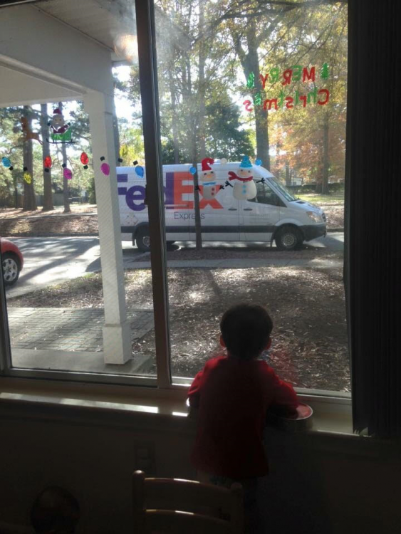 child looking out of a window at a Fedex truck