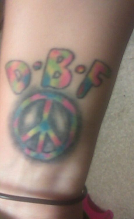 tattoo of initials and a peace sign