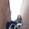 woman poses in her wheelchair in front of brick walls