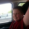 little boy in red shirt smiling in the car