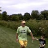man in green shirt that says 'blind runner' runs with a young boy in a field