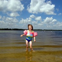 Photo of a young girl wearing swimmies in a lake