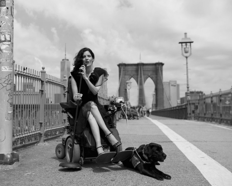 photograph of woman in motorized wheelchair with service dog on a bridge