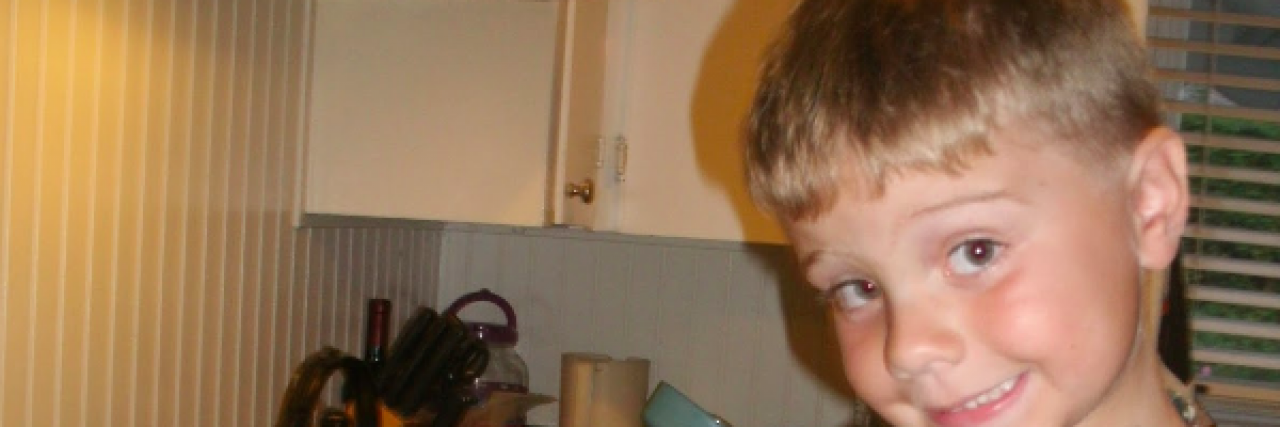 Contributor's young son smiling and wearing an apron at kitchen counter