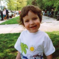 Smiling toddler boy outside standing on lawn