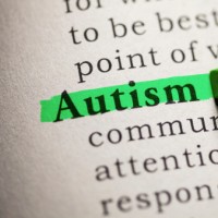 A highlighter pressed against a page and highling the word 'Autism'