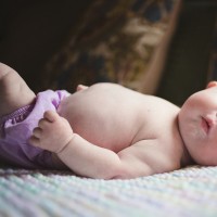 Baby with Down syndrome laying on its back and looking at the camera