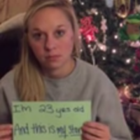 A woman holding up a notecard that says, "I'm 23 and this is my story."